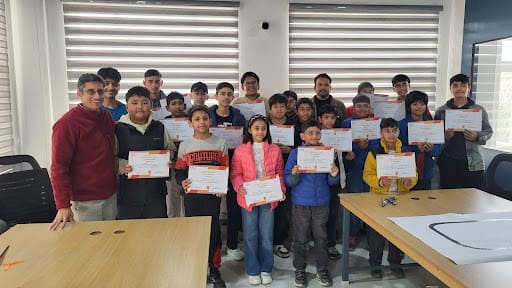 Students proudly holding certificates after completing a robotics workshop at Dharamshala.co, posing together with instructors in a classroom.